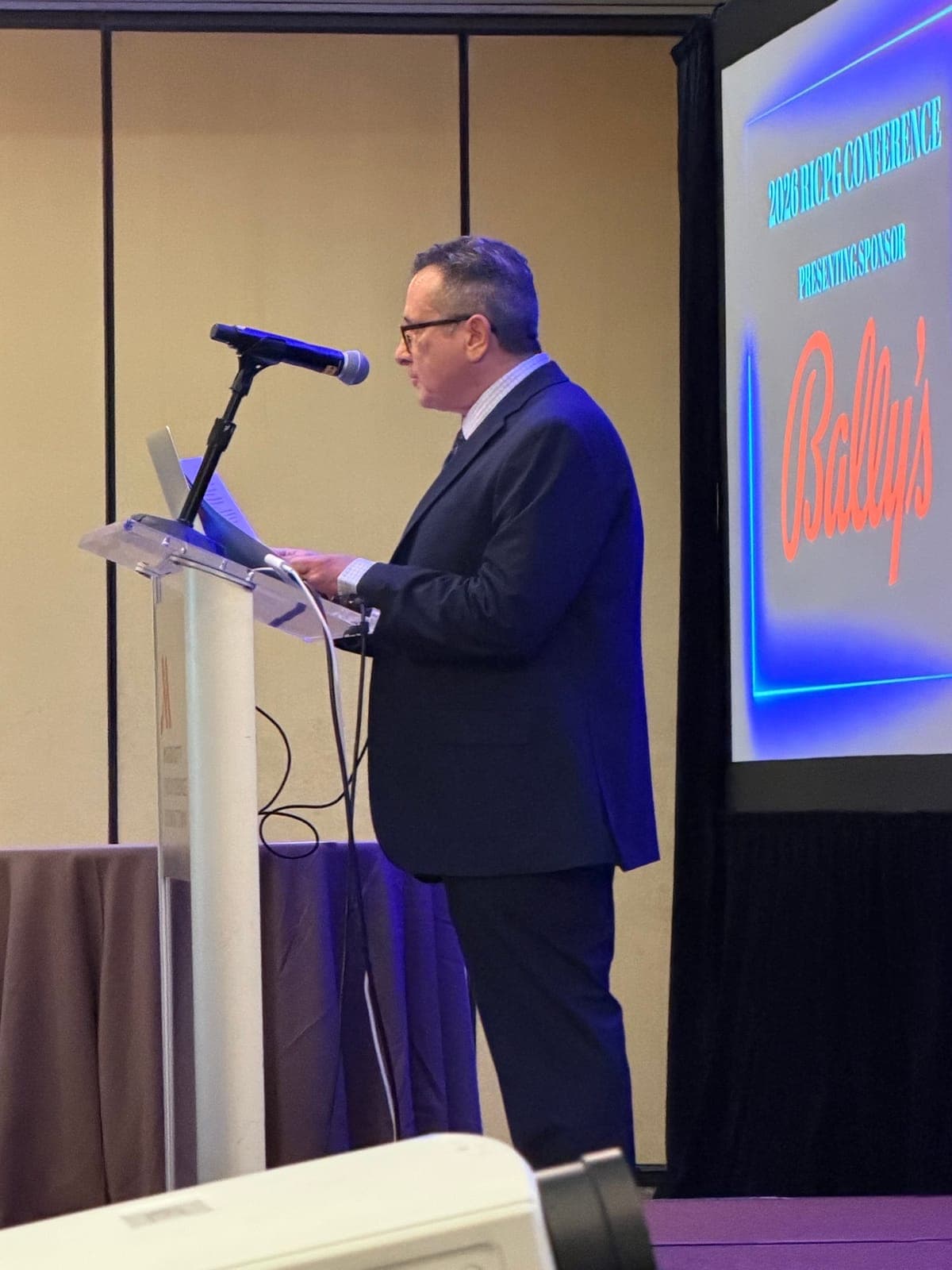 A speaker at the podium during the RICPG 2026 Annual Conference.