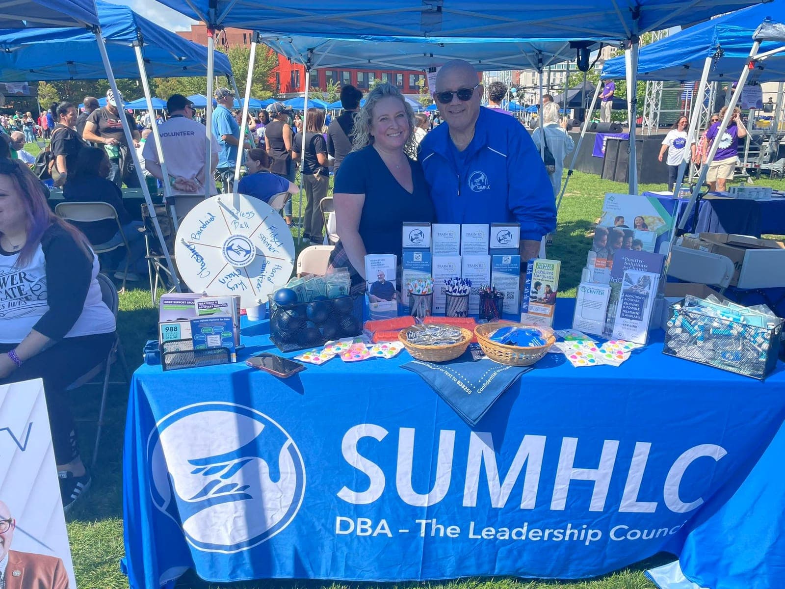 Two people at the SUMHLC table at an outdoor community event.